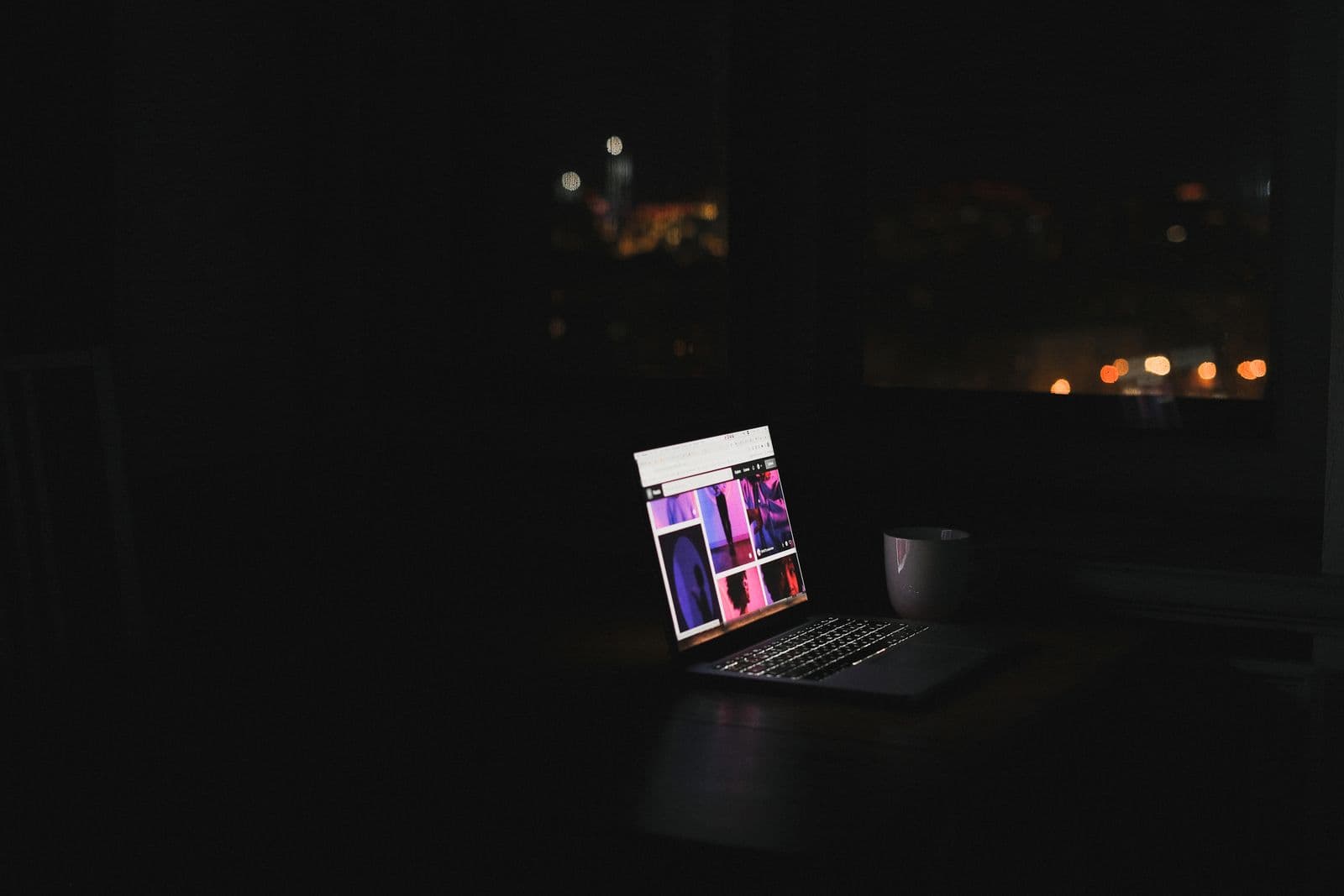 Ein Laptop leuchtet nachts allein in einem dunklen Zimmer